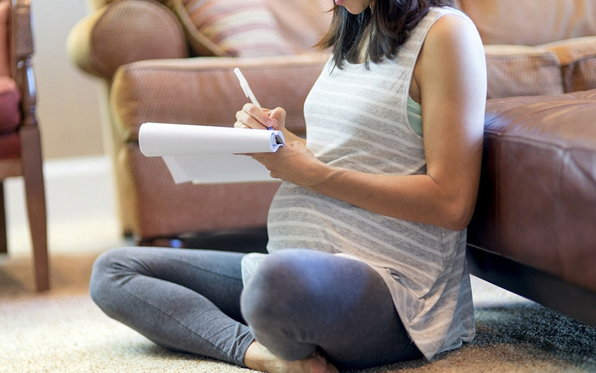 Auf der Checkliste zur Schwangerschaft macht sich eine Schwangere Notizen.
